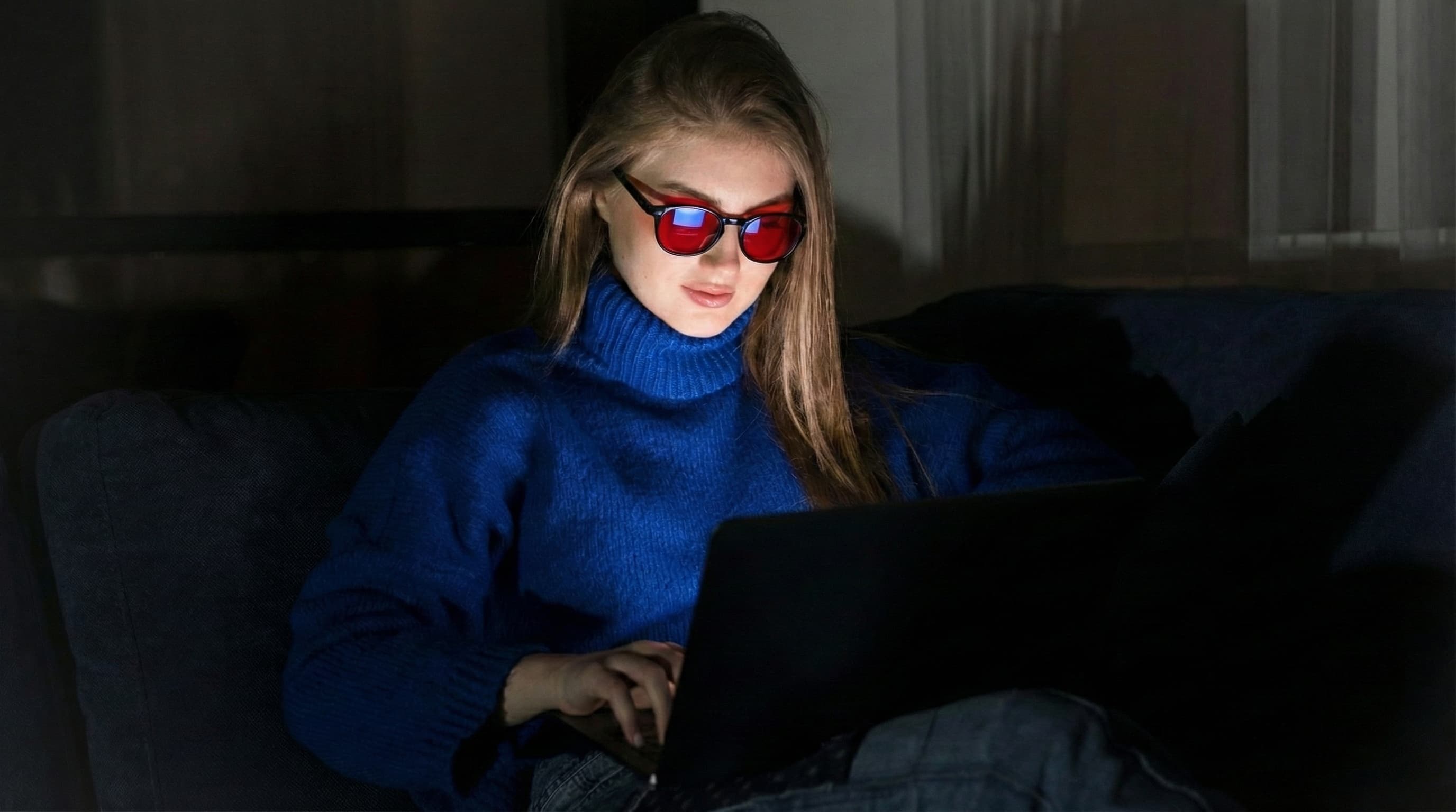 Persona usando gafas de luz azul frente a una pantalla por la noche en un entorno con poca luz