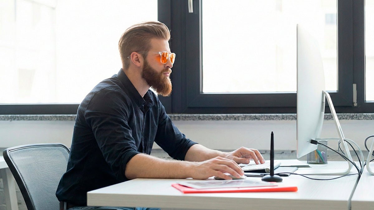 Persona usando gafas de luz azul frente al ordenador en uso diario